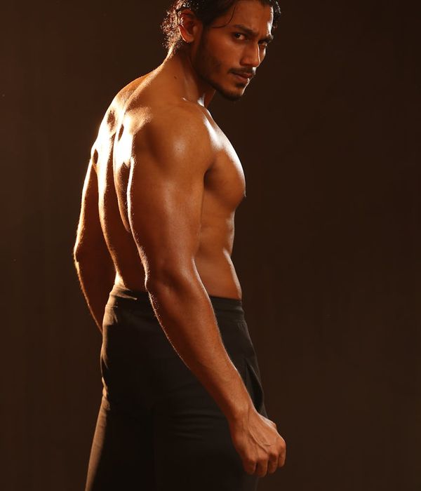 Athletic man focused on strength training in a dark modern studio environment.